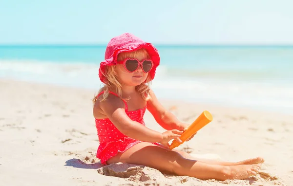 Sun protection - little girl with suncream at beach — Stock Photo, Image