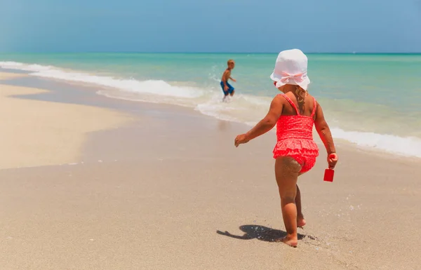 Malý chlapec a dívka hrát s vodou na pláži — Stock fotografie