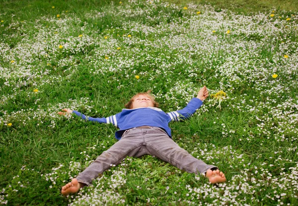 Маленький хлопчик відпочиває на зеленій траві — стокове фото