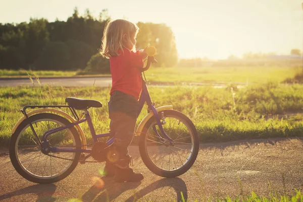 Bambina in sella alla bicicletta al tramonto — Foto Stock