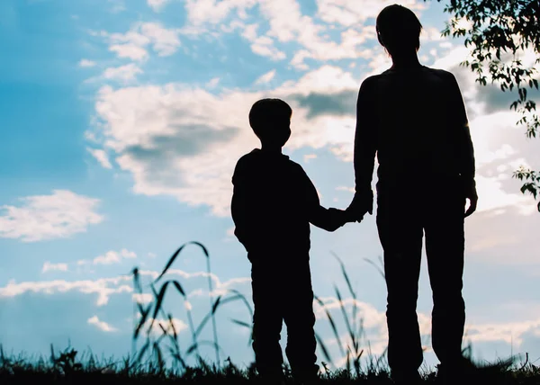 Silhueta de pai e filho de mãos dadas ao pôr do sol — Fotografia de Stock