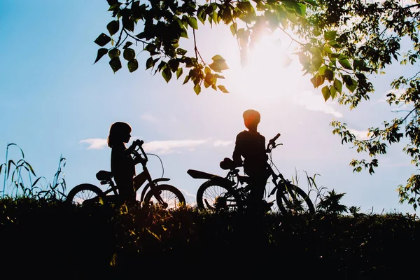 Маленький хлопчик і дівчинка катаються на велосипедах у природі заходу сонця — стокове фото