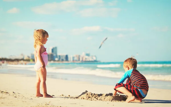 Menino e menina brincam com areia na praia — Fotografia de Stock