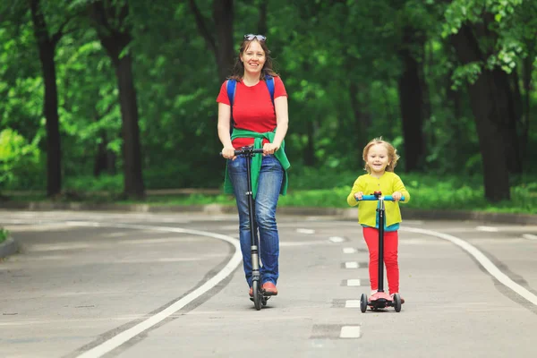 Glückliche Mutter und kleine Tochter fahren Roller — Stockfoto