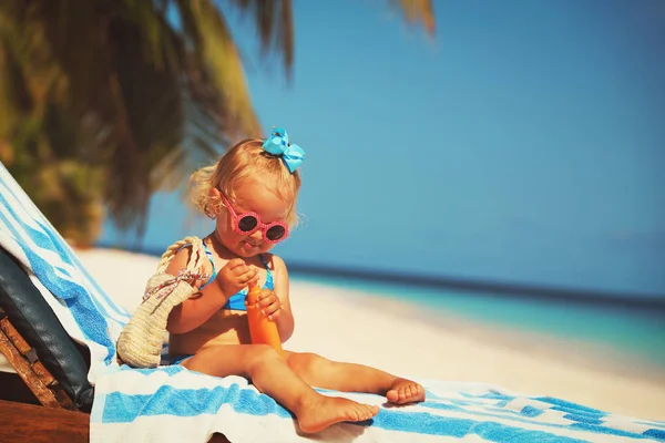 Sun protection - little girl with sunblock cream on beach — Stock Photo, Image