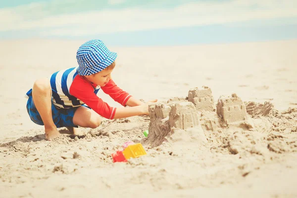 Kleine jongen spelen met zand op strand — Stockfoto