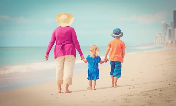 Gelukkig oma met kinderen lopen op strand — Stockfoto