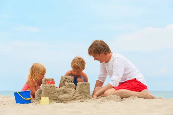 Vader en zoon en dochter gebouw kasteel op strand — Stockfoto