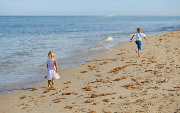 Kisfiú és a lány fut a strandon — Stock Fotó