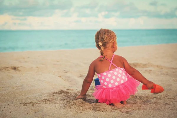 Niña jugando con arena en la playa — Foto de Stock