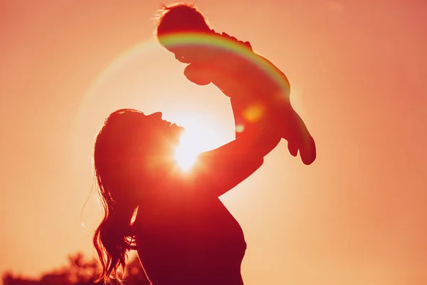 Moeder en kleine baby spelen bij zonsondergang — Stockfoto