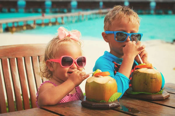 Malý chlapec a dívka pití kokosový koktejl na pláži — Stock fotografie