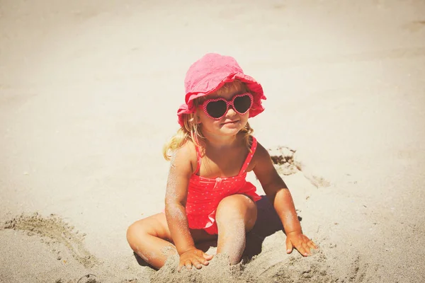 Mignonne petite fille jouer avec le sable sur la plage — Photo