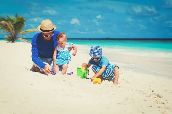 Отец с маленькой дочерью и сыном играют на пляже — стоковое фото