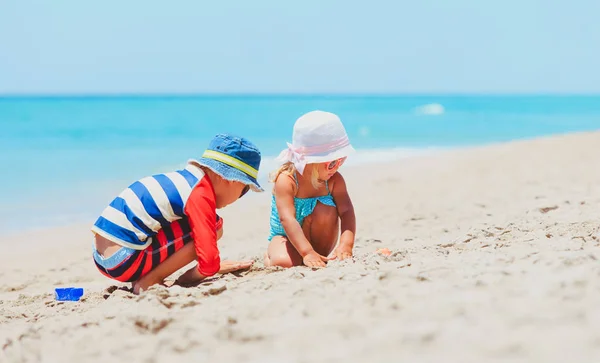 Menino e menina brincam com areia na praia — Fotografia de Stock