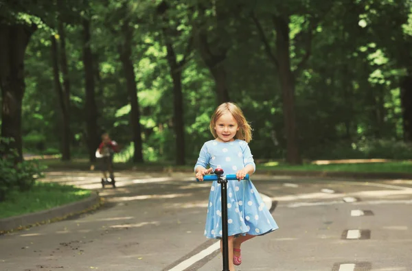 Carino bambina e ragazzo equitazione scooter in città — Foto Stock