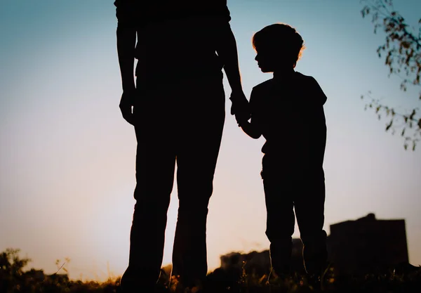 Silhouette di padre e figlio che si tengono per mano al tramonto — Foto Stock