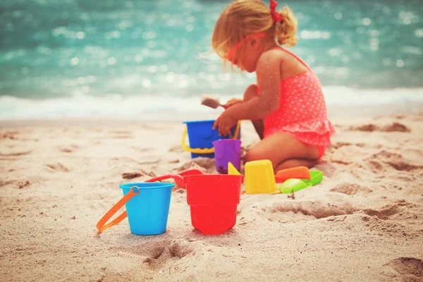 Tatlı küçük kız kumsalda kumla oynuyor.