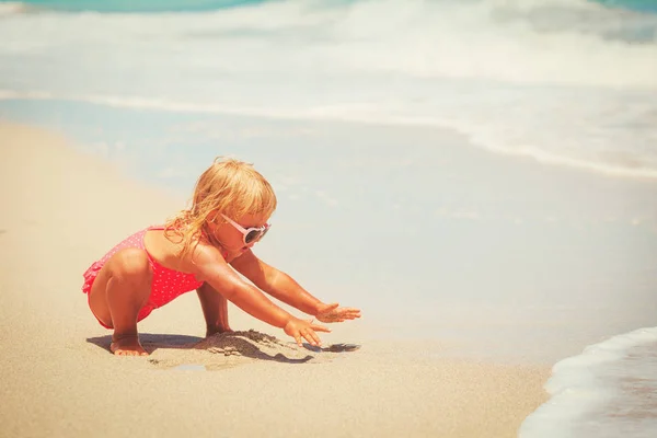 Schattig klein meisje spelen met zand op het strand — Stockfoto