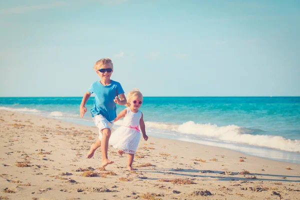 Kisfiú és a lány tengerparton fut — Stock Fotó