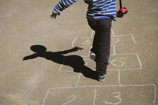Pequeno menino jogar hopscotch no playground — Fotografia de Stock