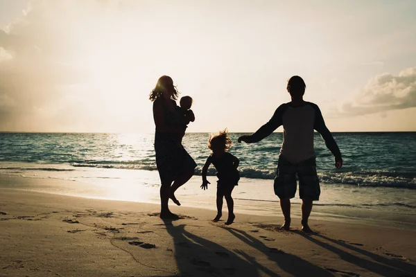 Família feliz com crianças brincam na praia do pôr do sol — Fotografia de Stock