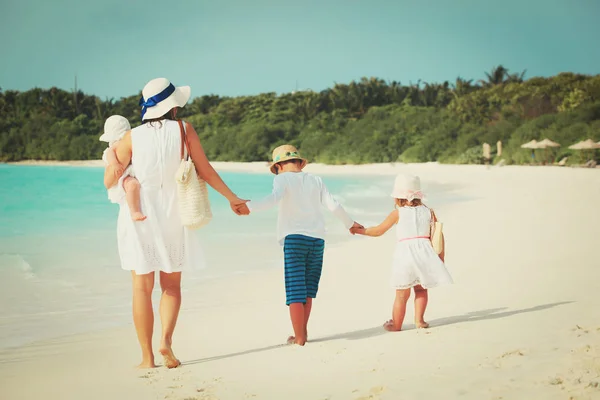 Moeder met drie kinderen lopen op strand — Stockfoto