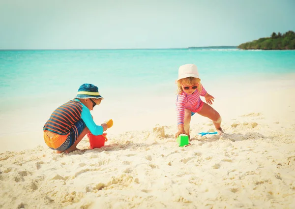 Мальчик и девочка играют с песком на пляже — стоковое фото