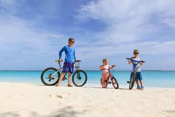 Vader met kleine zoon en dochter fietsen op strand — Stockfoto