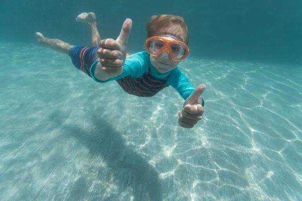 Szczęśliwy chłopiec pływanie pod wodą z kciuk w górę — Zdjęcie stockowe