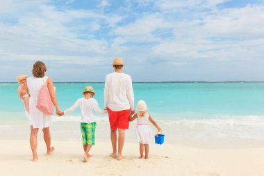Üç çocuklu mutlu bir aile sahilde yürüyor.