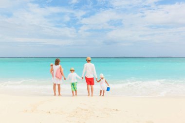 Üç çocuklu mutlu bir aile sahilde yürüyor.