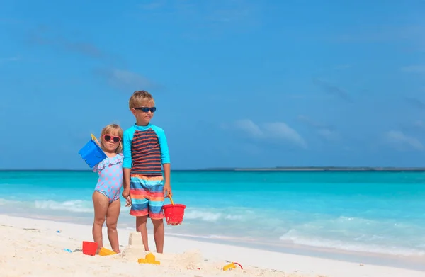 Menino e menina brincam com areia na praia — Fotografia de Stock