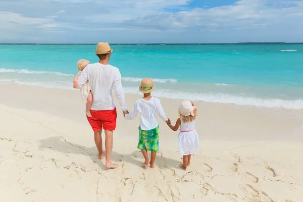 Vader en drie kinderen lopen op strand — Stockfoto