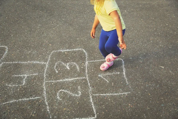 Menina jogar hopscotch no playground — Fotografia de Stock