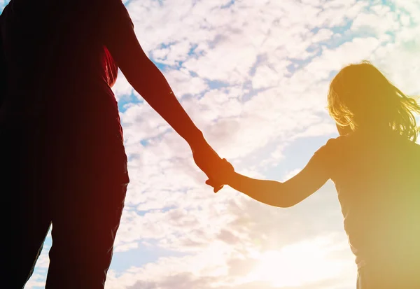 Silueta de madre e hija cogidas de la mano al atardecer — Foto de Stock