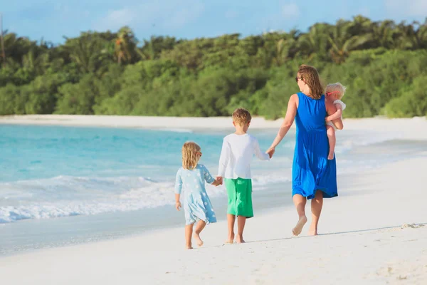 Moeder met drie kinderen lopen op strand — Stockfoto