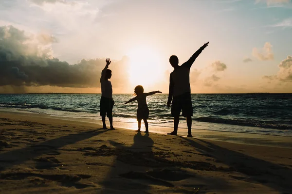 Vader en zoon en dochter silhouetten spelen op sunset beach — Stockfoto