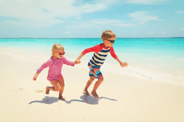 Menino e menina executar jogar na praia — Fotografia de Stock