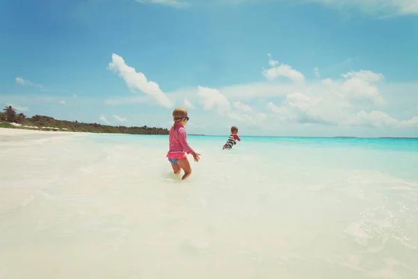 Klein meisje en jongen spelen met water op het strand — Stockfoto