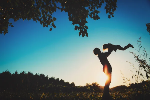 Baba ve küçük kızı gün batımında oynuyorlar.
