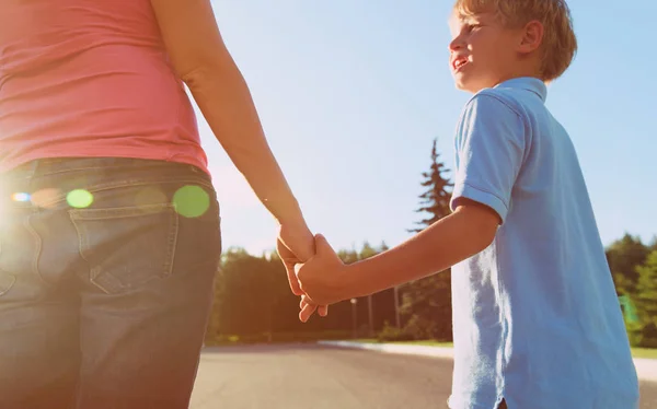 Mother holding hand of little son at sunset — Stock Photo, Image