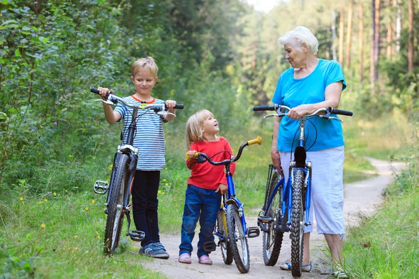 Avó feliz com crianças andando de bicicleta na natureza — Fotografia de Stock