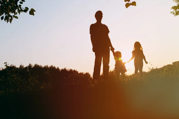 Батько з двома дочками ходить на заході сонця — стокове фото