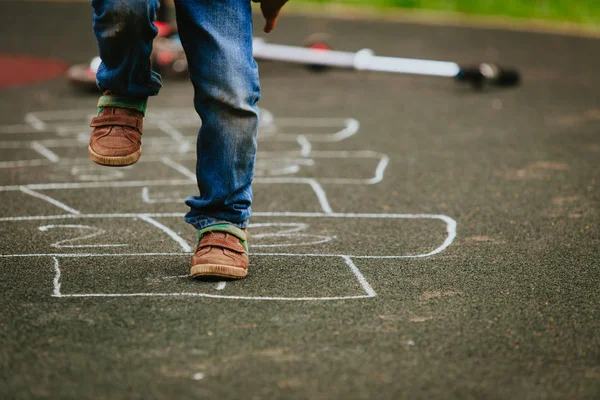 Pequeno menino jogar hopscotch no playground — Fotografia de Stock