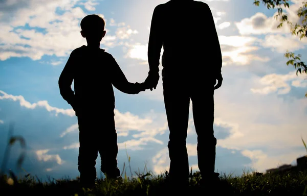 Silhouette von Vater und Sohn beim Händchenhalten bei Sonnenuntergang — Stockfoto