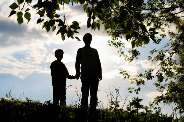 Silhouette di padre e figlio che si tengono per mano al tramonto — Foto Stock