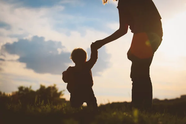 Moeder en baby eerste stappen maken bij zonsondergang — Stockfoto