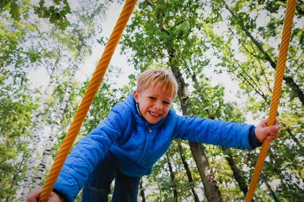 Glücklicher kleiner Junge klettert auf Spielplatz im Freien — Stockfoto