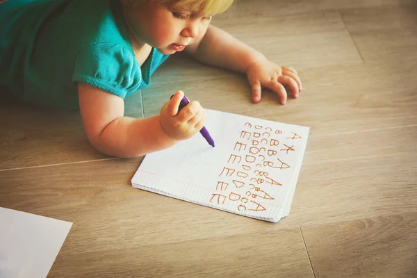 Маленькая девочка учится писать письма — стоковое фото